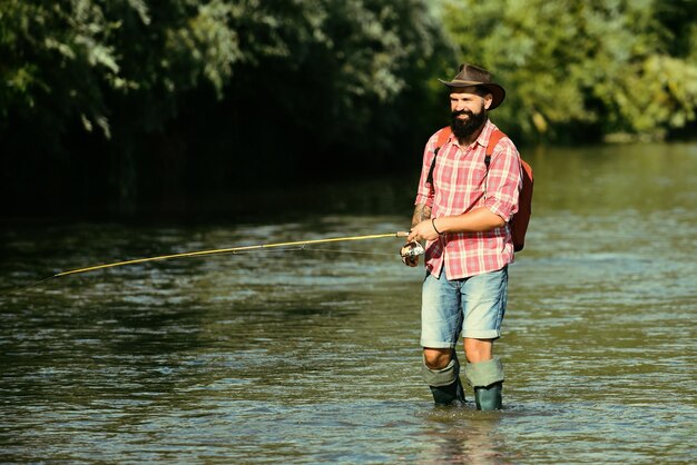 Hombre pescando y relajándose mientras disfruta de la afición un pescador con caña de pescar en el río pescador un