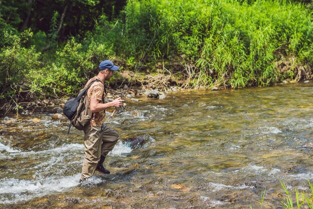 Hombre pescando en un río de montaña con un spinning ultraligero utilizando wobblers de pesca. Se enganchó su anzuelo por algo