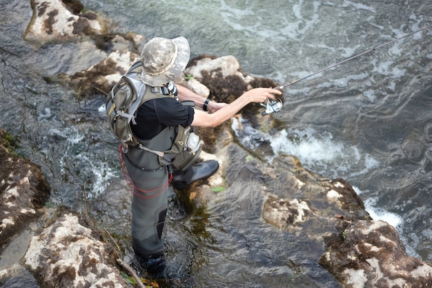 Hombre pescando en el río. Pescador en el agua. espectáculo de pescadores uso de la técnica de pesca. Barra. Hobby y actividad deportiva.