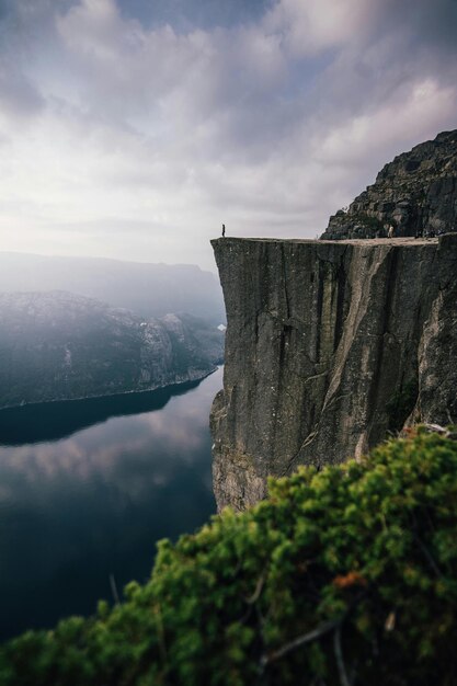 Foto un hombre está de pie en un acantilado con vistas a un cuerpo de agua