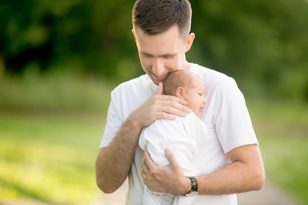 Foto hombre de pie con un bebé en brazos en el parque