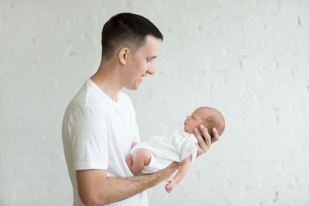 Foto hombre de pie con un bebé en brazos