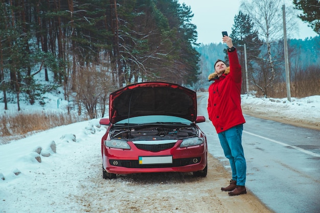 Hombre de pie cerca de coche roto en carretera nevó el clima invernal. copia espacio