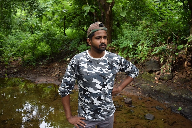 Foto hombre de pie contra el río en el bosque