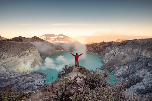 Hombre de pie en la cresta del cráter al amanecer por la mañana