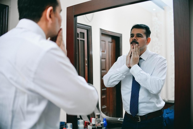 Hombre de pie enfrente del espejo use camisa blanca y corbata modelo paquistaní indio