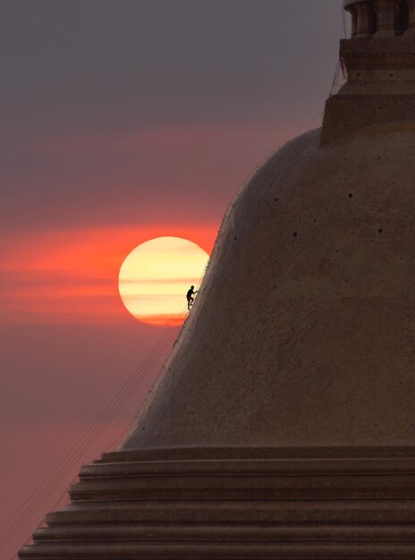 Foto hombre de pie en la escalera contra el cielo durante la puesta de sol