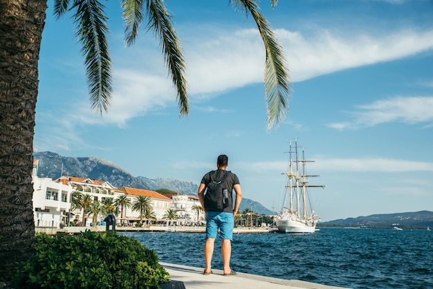 Hombre de pie junto al mar con una hermosa vista de la bahía con un gran barco