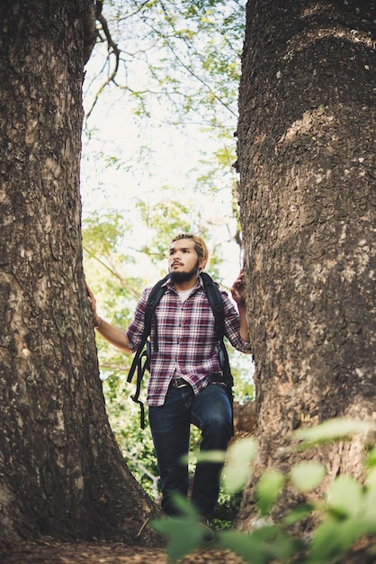 Foto hombre de pie junto al tronco de un árbol en el bosque