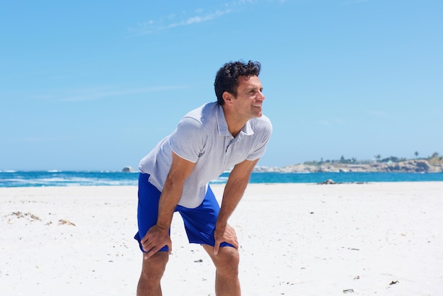 Hombre de pie con las manos en la rodilla en la playa