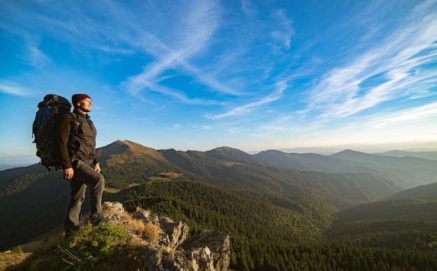 El hombre de pie en la montaña soleada