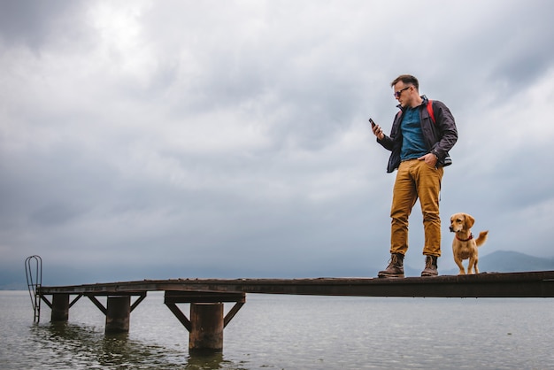 Hombre de pie en el muelle y utilizando teléfonos inteligentes