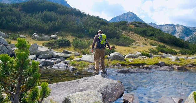 Foto un hombre está de pie en un río con una mochila en la espalda