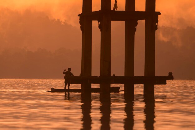 Hombre de pie en el río durante la puesta de sol