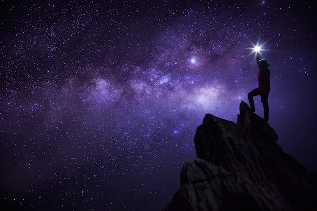 Foto hombre de pie en la roca contra el cielo por la noche