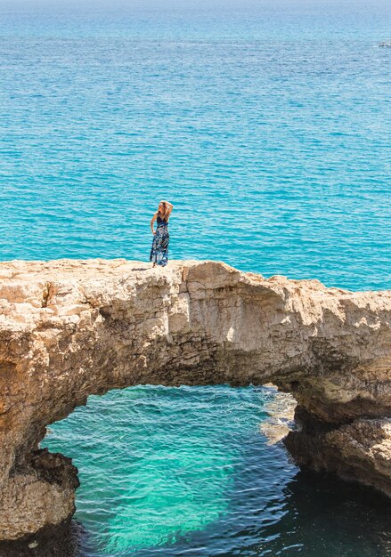 Foto hombre de pie en una roca junto al mar