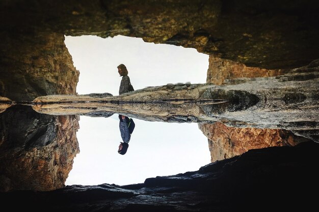 Foto hombre de pie en la roca por el mar contra el cielo