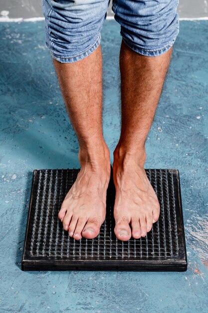 Foto hombre de pie sobre masajeador de madera de pie natural con clavos