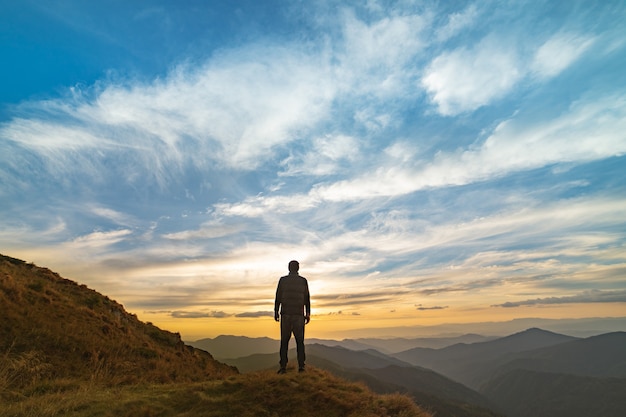 El hombre de pie sobre la roca con una pintoresca puesta de sol