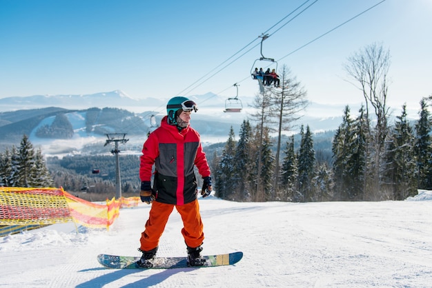 Foto hombre de pie sobre su tabla de snowboard en una pista de esquí en el resort de invierno