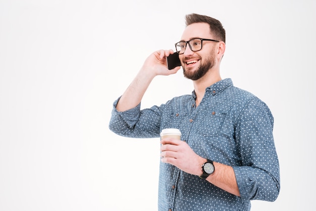 Hombre de pie con una taza de café y hablando por teléfono