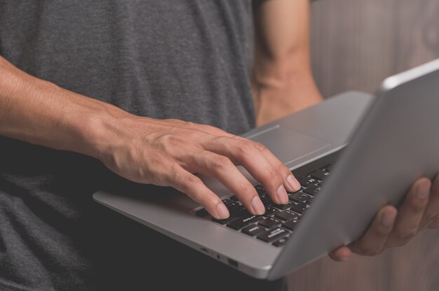 Un hombre de pie usando una computadora portátil