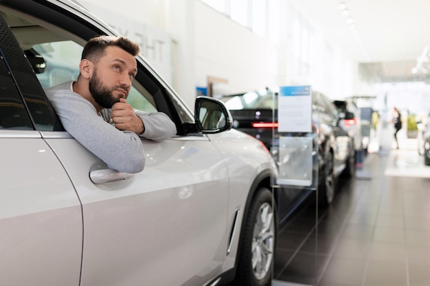 Un hombre piensa en comprar un auto nuevo para su familia en un concesionario de autos