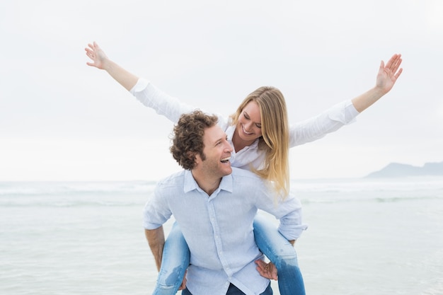 Hombre piggybacking mujer en la playa