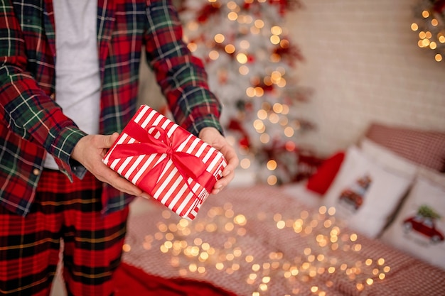 hombre en pijama sosteniendo un regalo de navidad