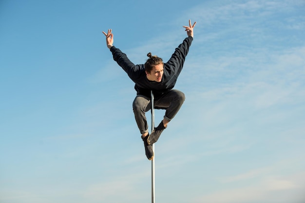 El hombre en el pilón hace el ejercicio con el telón de fondo del cielo azul.