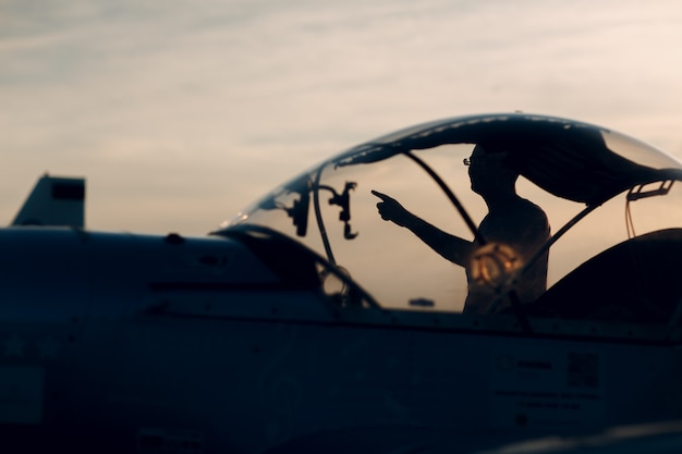 Hombre piloto de pie junto a un pequeño avión privado.