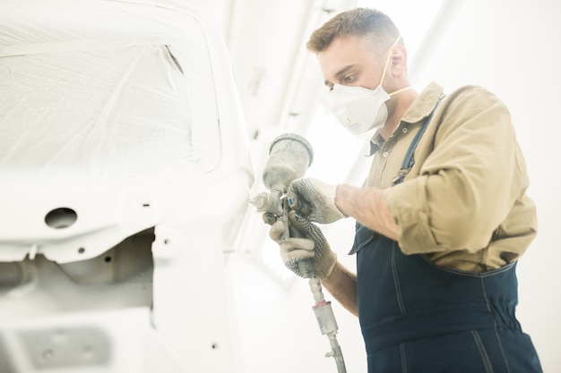 Hombre pintando auto en taller