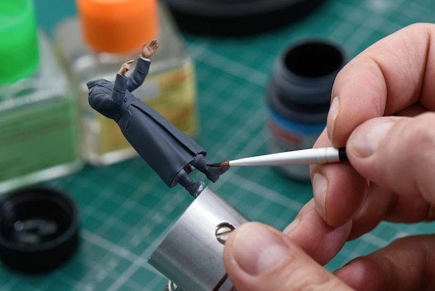 Un hombre pintando figura de soldado de la segunda guerra mundial de plástico en uniforme