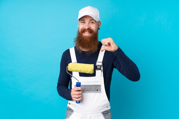 Hombre pintor con barba larga sobre azul aislado orgulloso y satisfecho de sí mismo