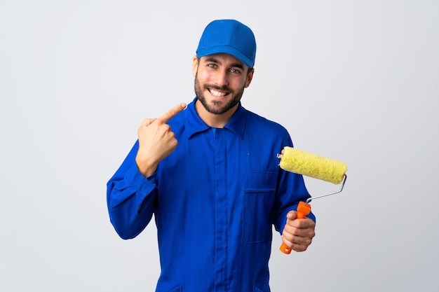 Hombre pintor sosteniendo un rodillo de pintura aislado en blanco dando un pulgar hacia arriba gesto