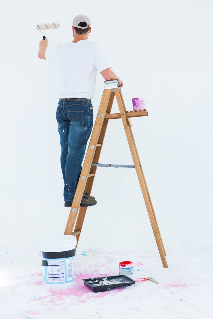 Foto hombre en la pintura de la escalera con el rodillo