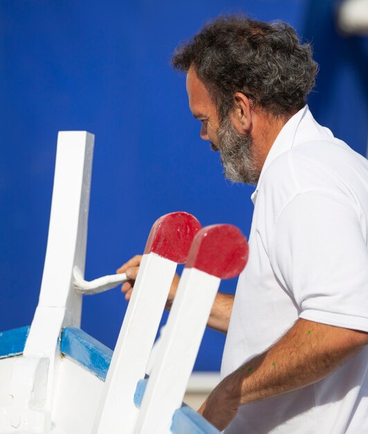 Foto hombre, pintura, tradicional, bote de remos, con, cepillo