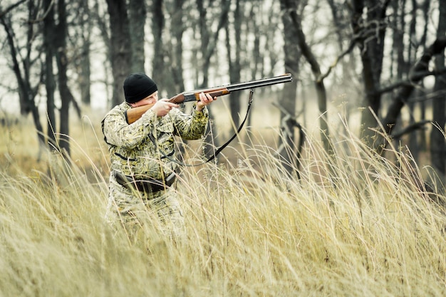 Un hombre con una pistola, en el contexto de un bosque de otoño.