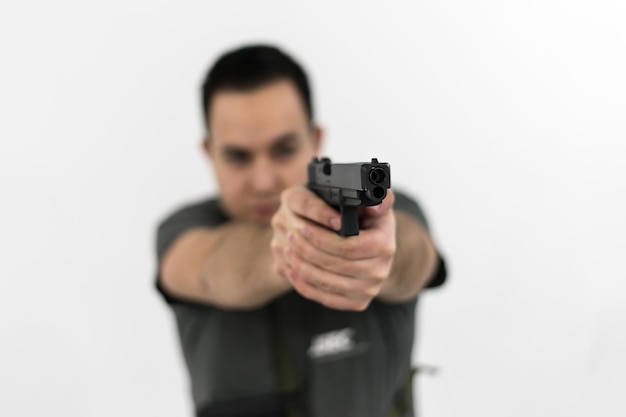 Foto hombre con una pistola contra un fondo blanco