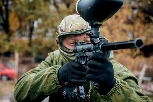 Hombre con pistola jugando en paintball. Al aire libre