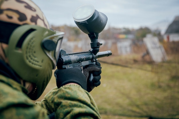 Hombre con pistola jugando en paintball. Al aire libre