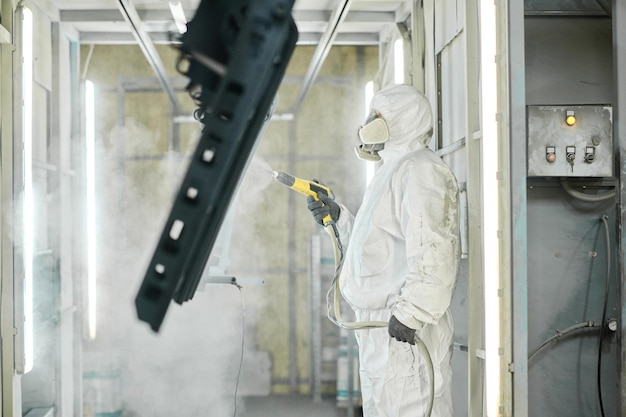 Foto hombre con pistola de pintura de metal en la fábrica.