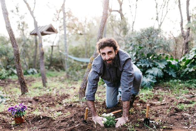 Hombre plantando flores en su jardín