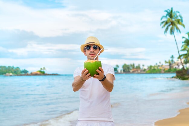 Un hombre en la playa bebe coco.