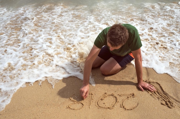 Un hombre en la playa está pintando en la arena 2018