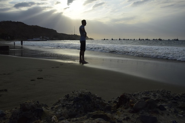 Un hombre se para en la playa y observa la puesta de sol Máncora Perú