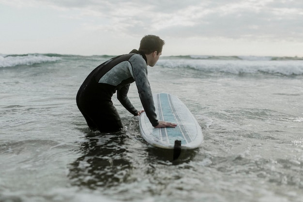 Foto hombre en la playa con su tabla de surf
