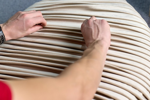 El hombre pliega la tela por encargo en una fábrica de muebles
