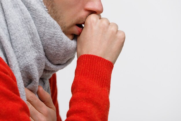 Foto hombre poco saludable en suéter naranja que sufre de tos pulmonar debido a resfriado, gripe