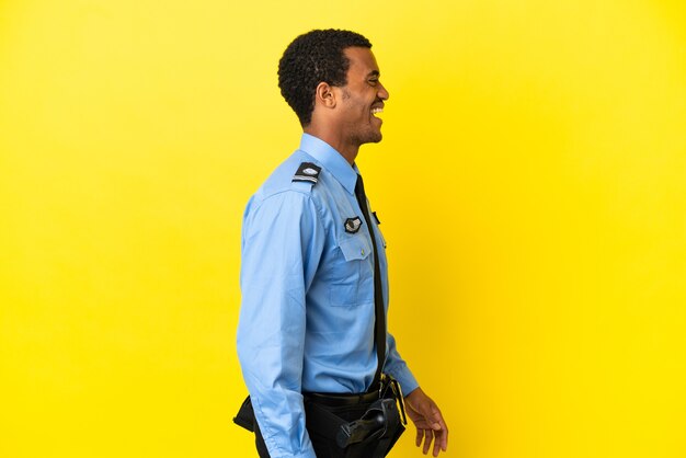 Hombre de la policía afroamericana sobre fondo amarillo aislado riendo en posición lateral